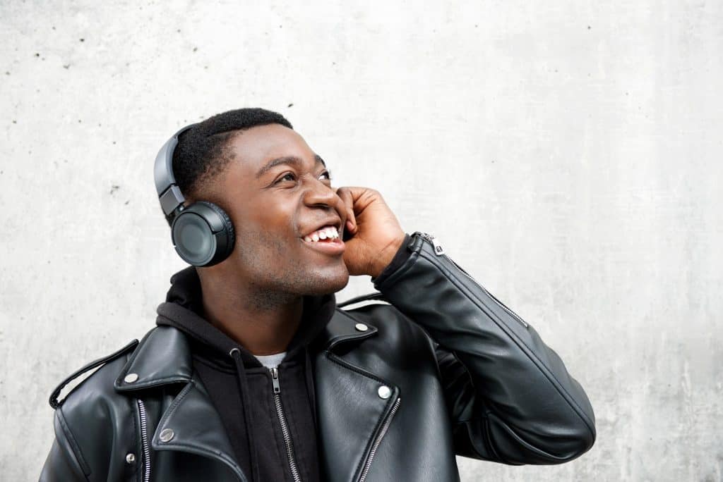 smiling young black man listening to music with headphones